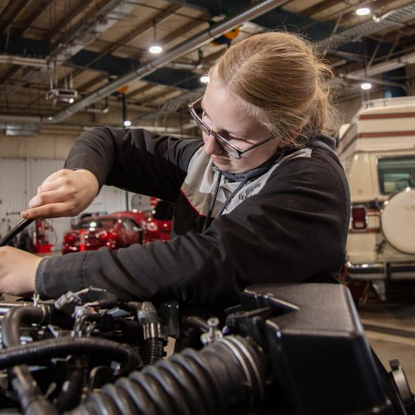 an auto student fixes a car engine