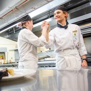 To people in chef's whites clasping hands in celebration. 